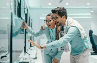 Um homem e uma mulher vendo uma tv em uma loja.