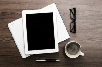 Um tablet ao lado de uma xícara.